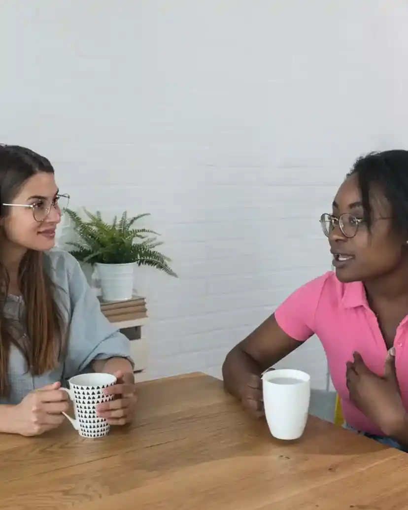 Two friends talking over mugs of coffee at a kitchen table